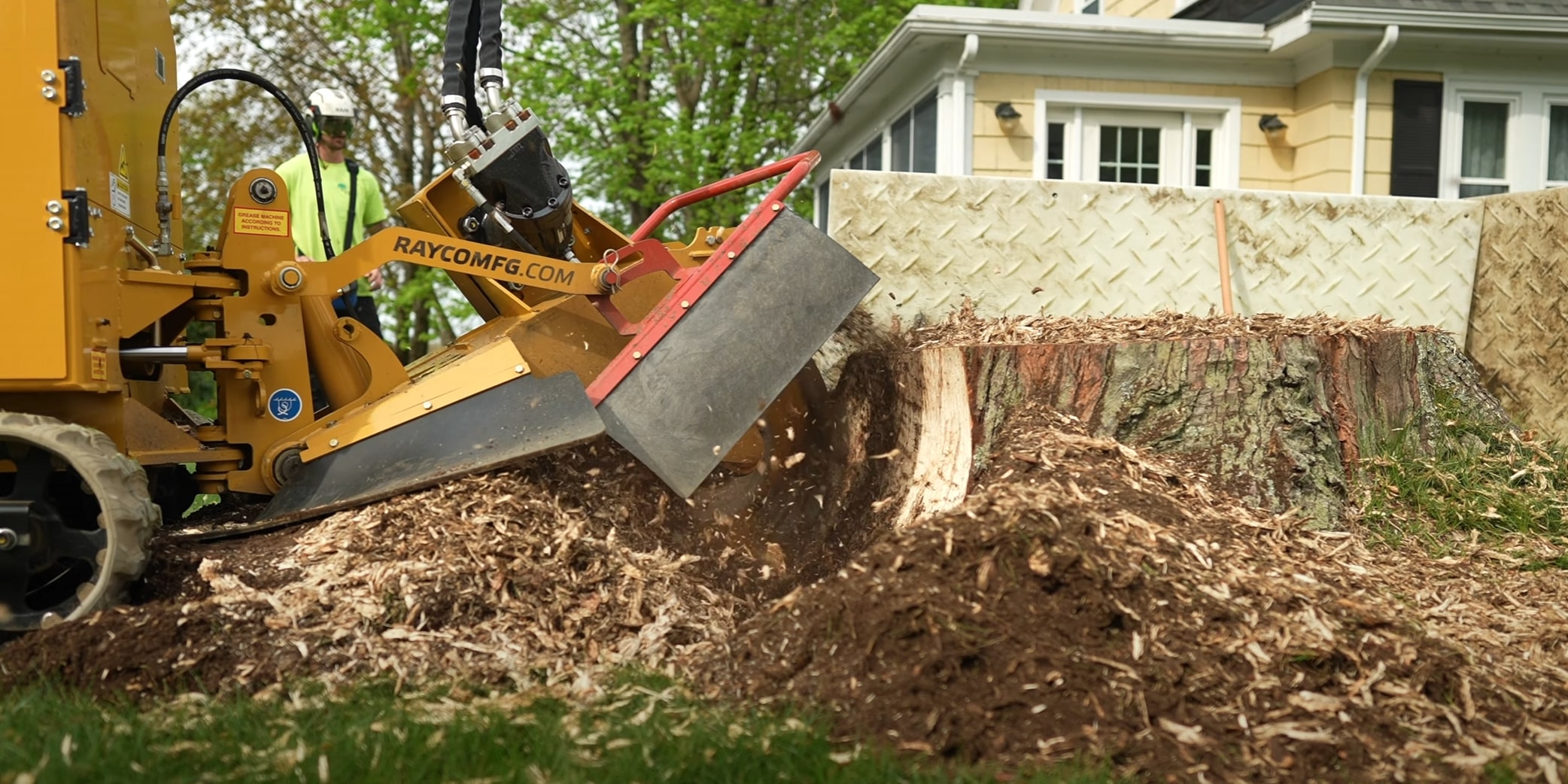 Professional stump grinding equipment removing large tree stump in residential backyard